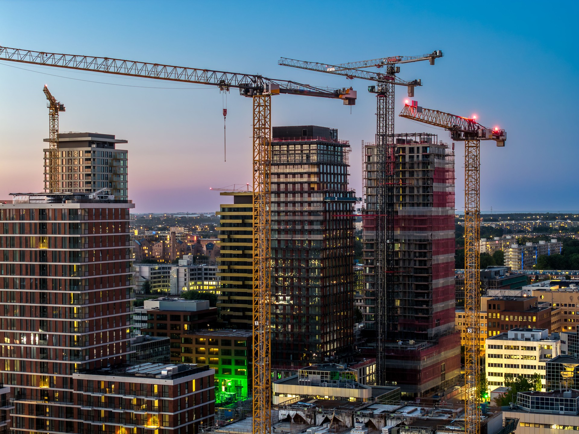 Construction cranes dominate Amsterdam South skyline at dusk